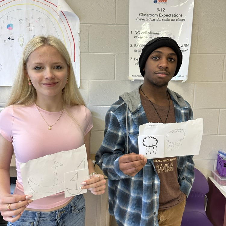 two students pose with their drawings