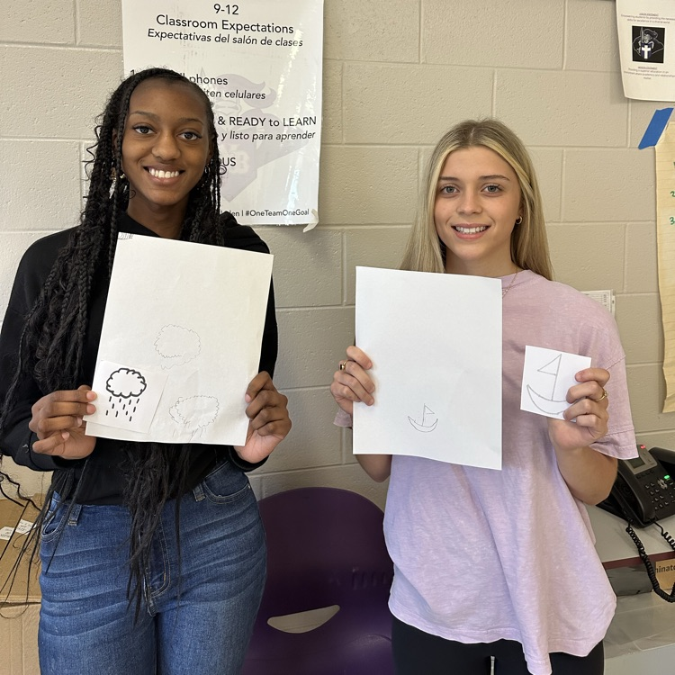 two female students pose with their drawings