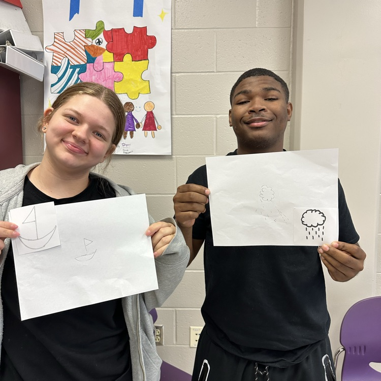 two students pose with photos