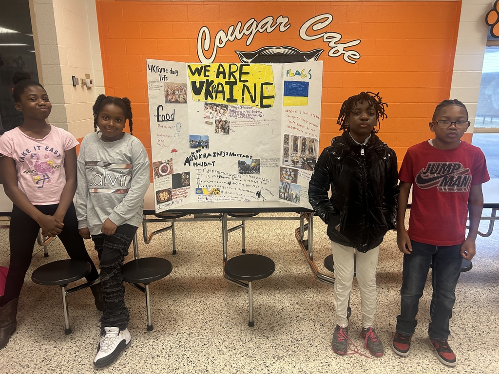Five ETMS students pose next to their Ukraine culture project board titled “We Are Ukraine,” highlighting Ukrainian daily life, food, holidays, and the country’s flag.