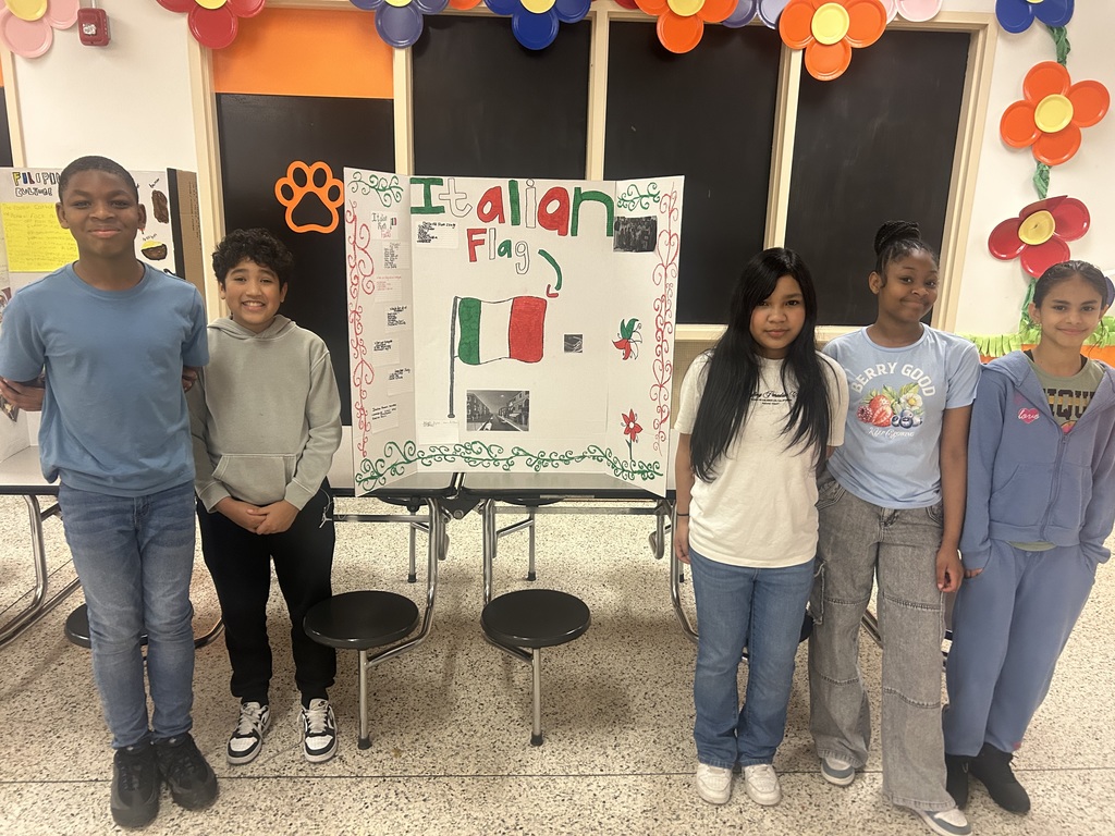 Five students present a tri-fold board about Italy, displaying the Italian flag along with facts about the country’s culture, landmarks, and traditions.
