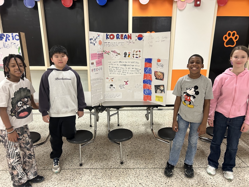 Five students stand with a tri-fold display about Korean culture, featuring the South Korean flag, traditional clothing, food, language, and cultural customs.