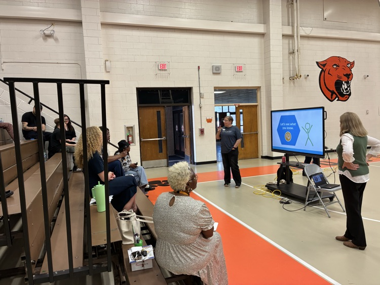 nine people in a gym listening to a presentation