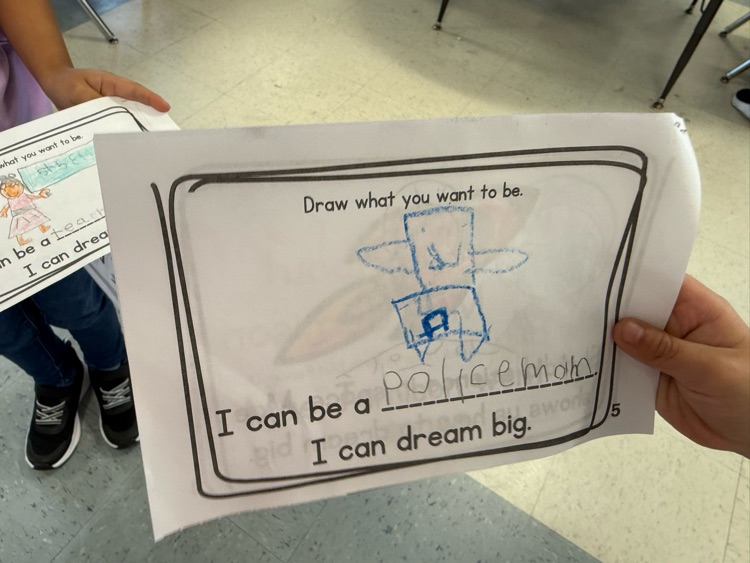 Student holding a worksheet drawing of a police officer as their future dream job.