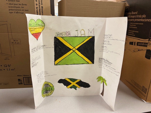 Student project board about Jamaica displaying the Jamaican flag, a map of the island, and facts about the country’s culture and geography.