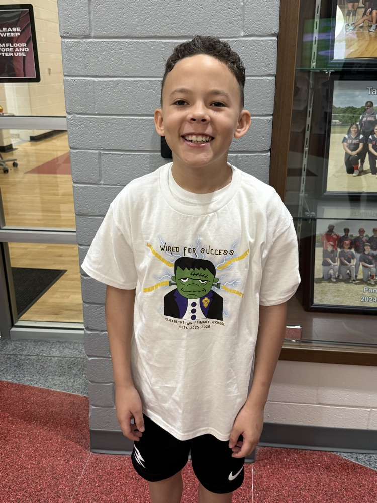 Student Jeremiah Y. smiles while wearing the Elizabethtown Primary School Beta Club shirt he designed featuring the “Wired for Success” graphic