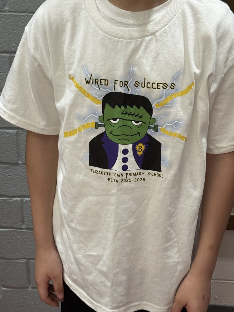Student Jeremiah Y. smiles while wearing the Elizabethtown Primary School Beta Club shirt he designed featuring the “Wired for Success” graphic