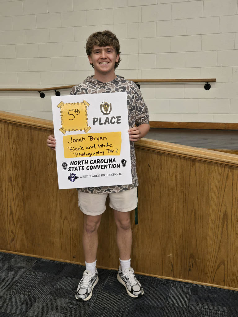 West Bladen High School student holds a "Premier Performers" award certificate while standing inside a school building