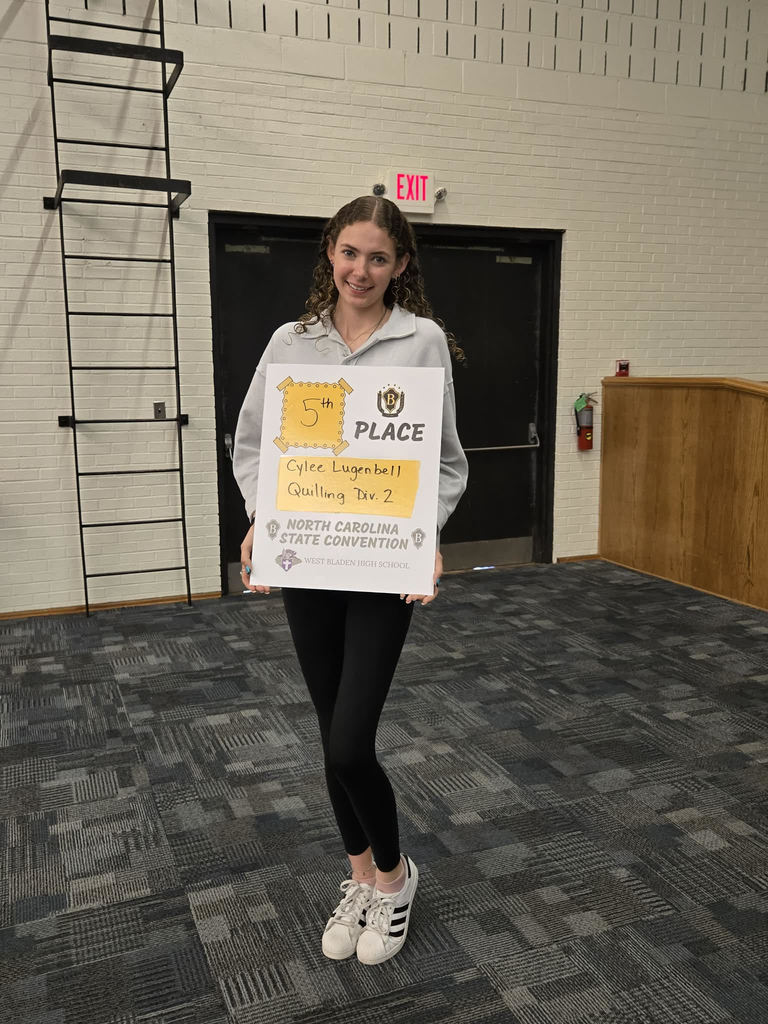 West Bladen High School student holds a "Premier Performers" award certificate while standing inside a school building