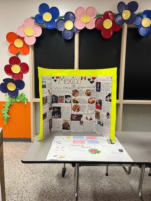 Student project about Mexico displayed on a classroom table with sections about traditional clothing, food, and interesting cultural facts.