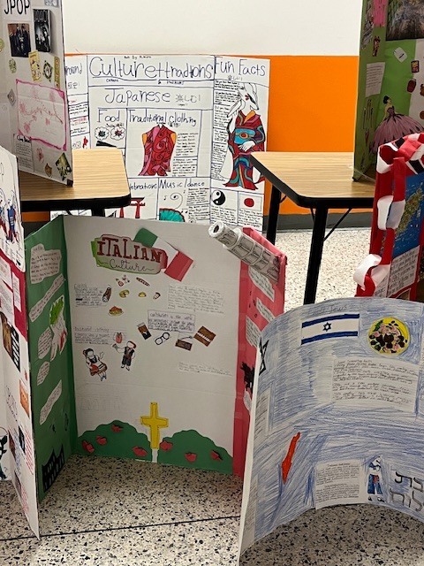 Several student display boards featuring cultures such as Italy, Israel, and Japan with drawings, maps, and facts about traditions and daily life.