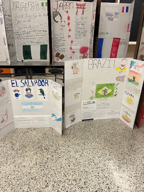 Student projects highlighting Nigeria, Japan, Brazil, and El Salvador with hand-drawn illustrations, maps, and facts about animals, food, and culture.