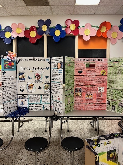 Student cultural displays about Honduras and African American culture presented on large boards with photos, food examples, history, and traditions.