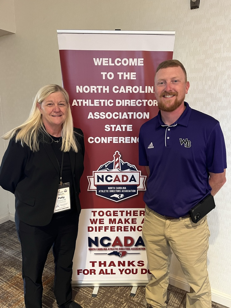 EB and WB athletic director staying in front of a NCADA banner together