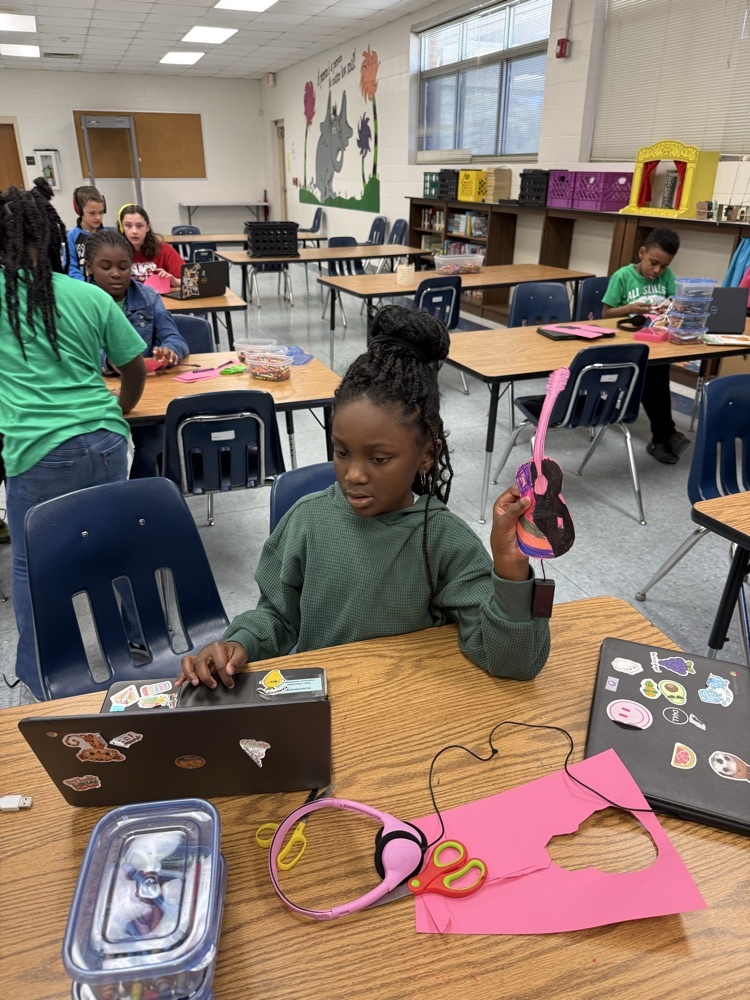 1. Student holding a colorful handmade paper guitar with a micro:bit attached, showing how it functions as an electric instrument