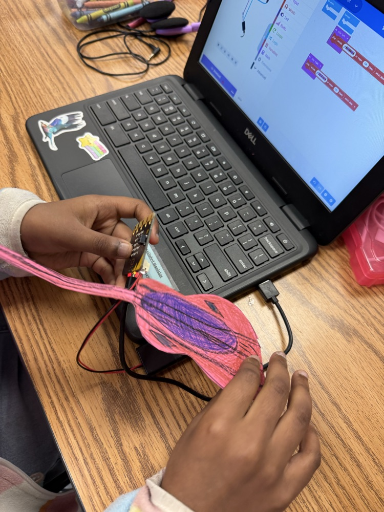 Student holding up a completed paper guitar with a micro:bit attached, demonstrating their finished STEM project