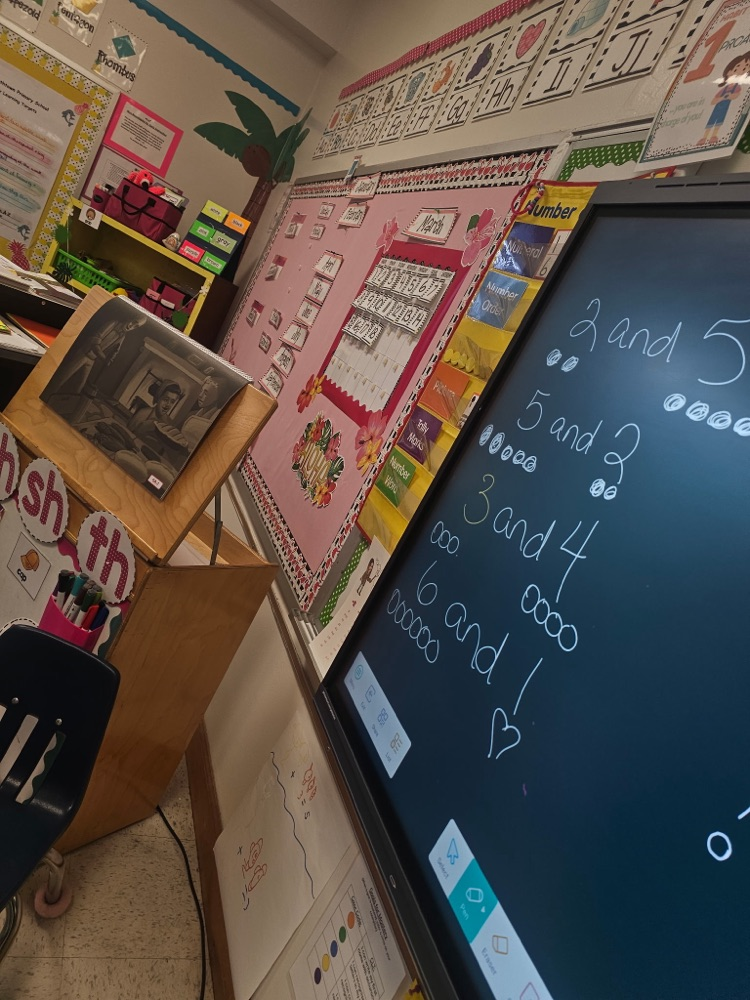 A student uses a stylus on a large digital board to solve composing and decomposing number problems, showing combinations that make 7 with drawn dots.
