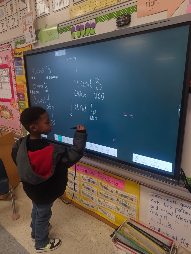 A student uses a stylus on a large digital board to solve composing and decomposing number problems, showing combinations that make 7 with drawn dots.