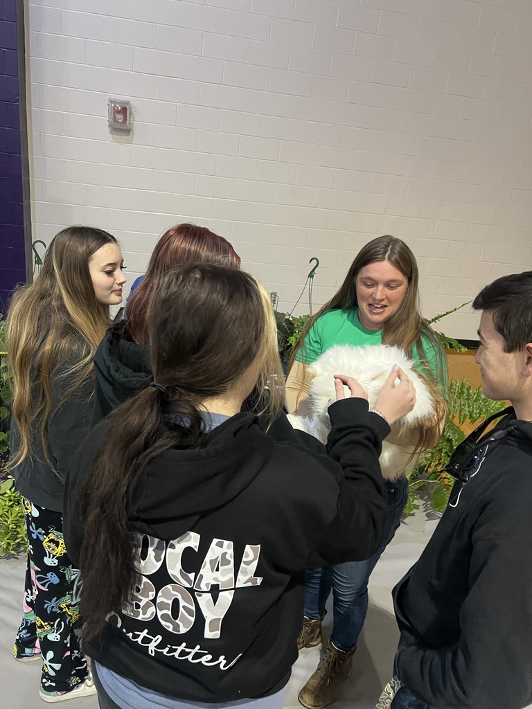 Three female students smiling and talking together at the West Bladen CTE Career Fair in a gymnasium