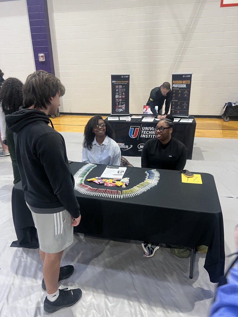 Students at West Bladen CTE Career Fair speak with a recruiter at the Universal Technical Institute table in a gymnasium