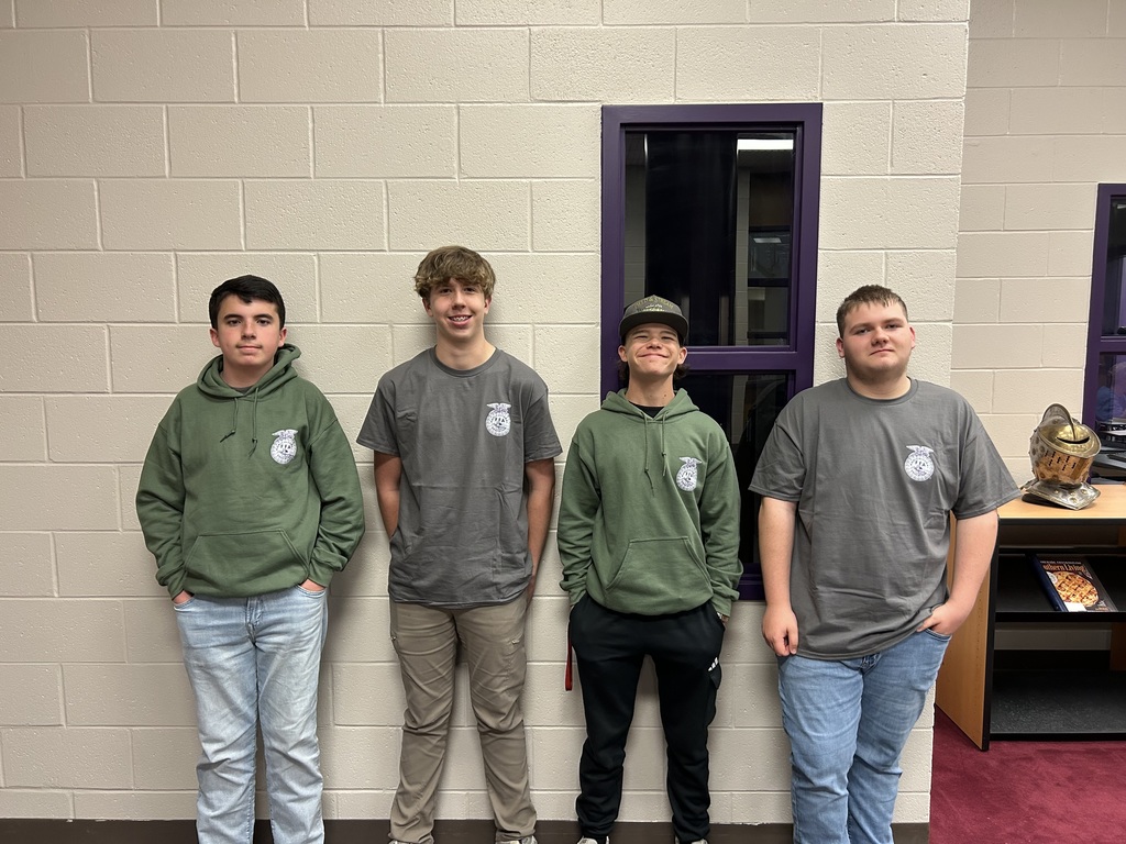 Four young men wearing FFA (Future Farmers of America) shirts and hoodies standing together in a school hallway