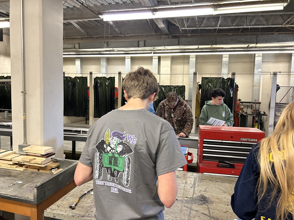 Students in an agricultural workshop working near a red Craftsman toolbox and welding booths