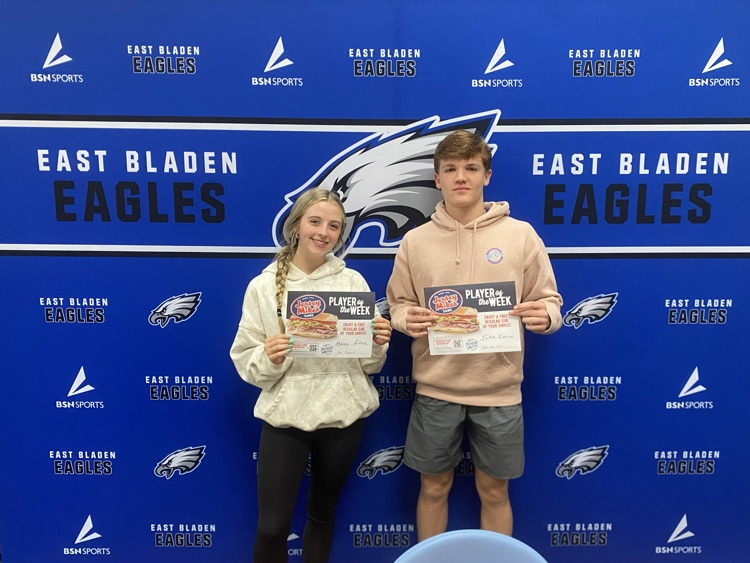 two students in front of a East Bladen eagle backdrop holding jersey Mike’s certificates