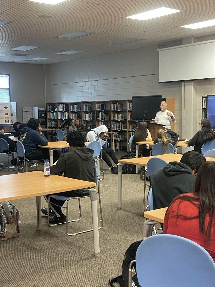 students in a library while a man presents to them about financial literacy