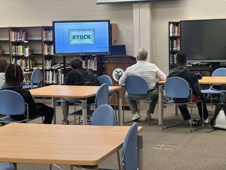 students in a library while a man presents to them about financial literacy