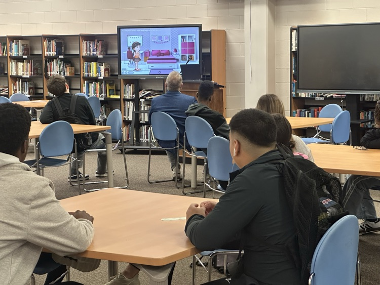 students in a library while a man presents to them about financial literacy