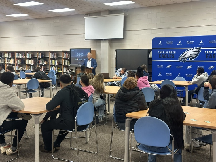 students in a library while a man presents to them about financial literacy