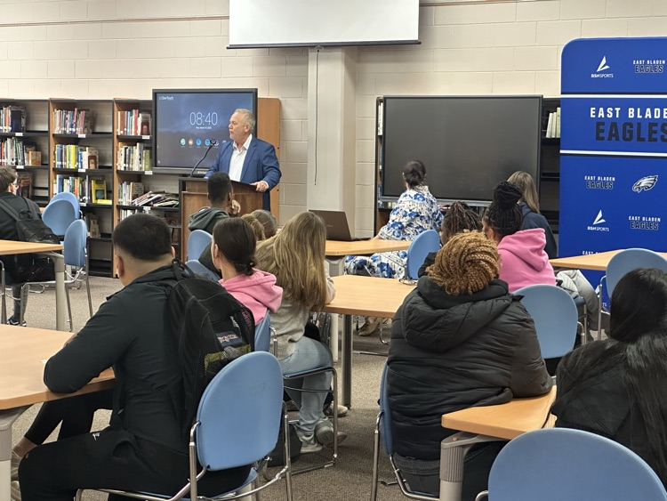 students in a library while a man presents to them about financial literacy