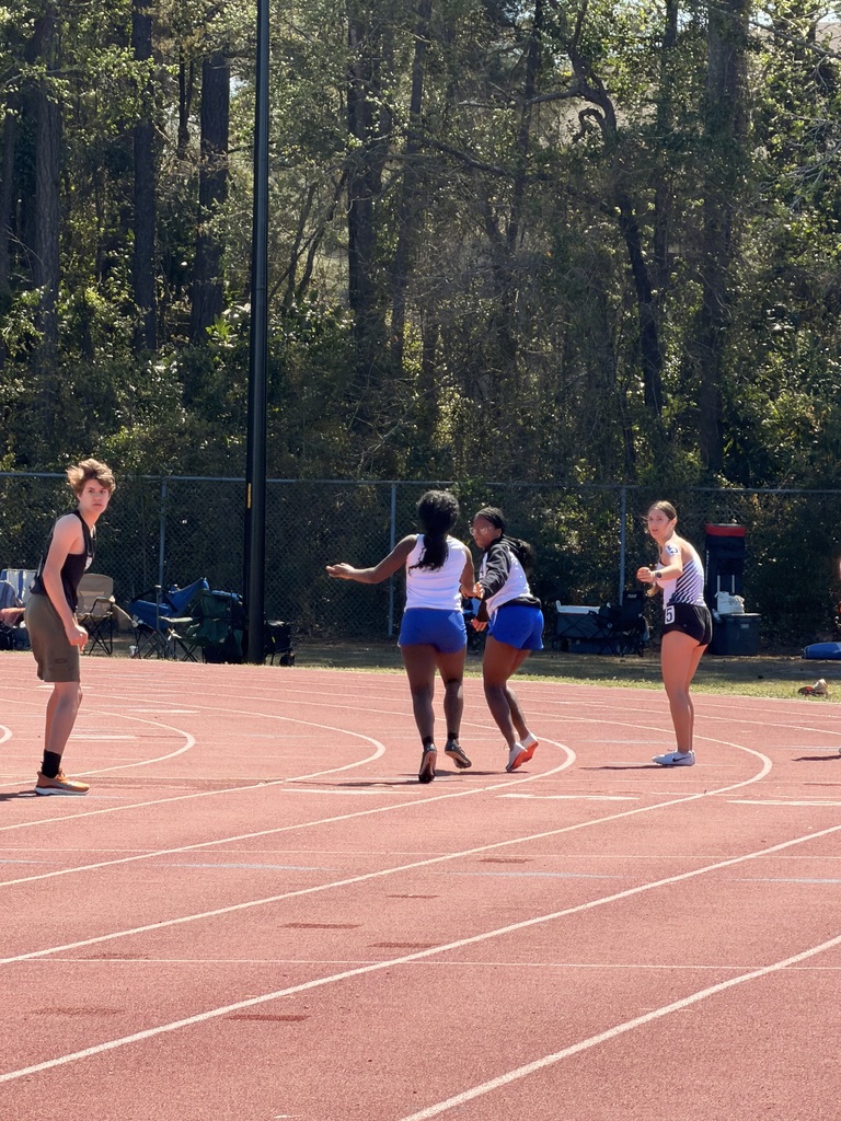Female track student passing baton to another femal track student.