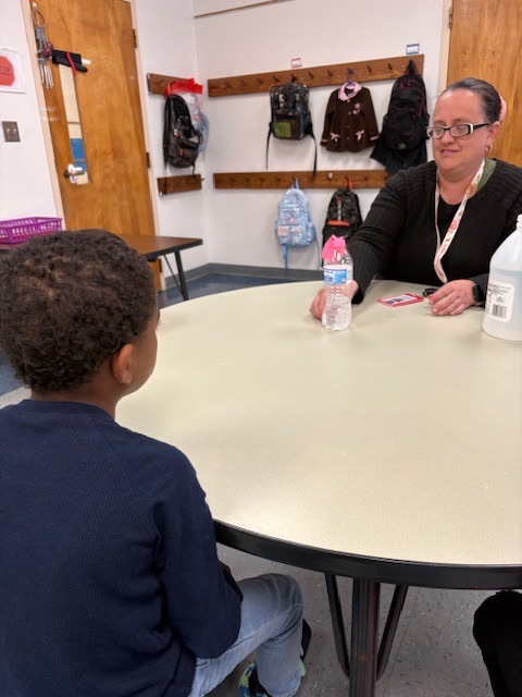 Students watch as a balloon inflates on top of a bottle during a classroom experiment demonstrating a chemical reaction that produces gas.