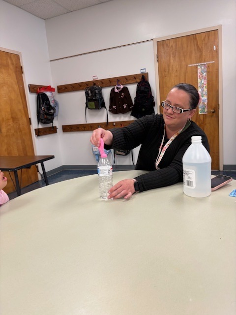 Students watch as a balloon inflates on top of a bottle during a classroom experiment demonstrating a chemical reaction that produces gas.