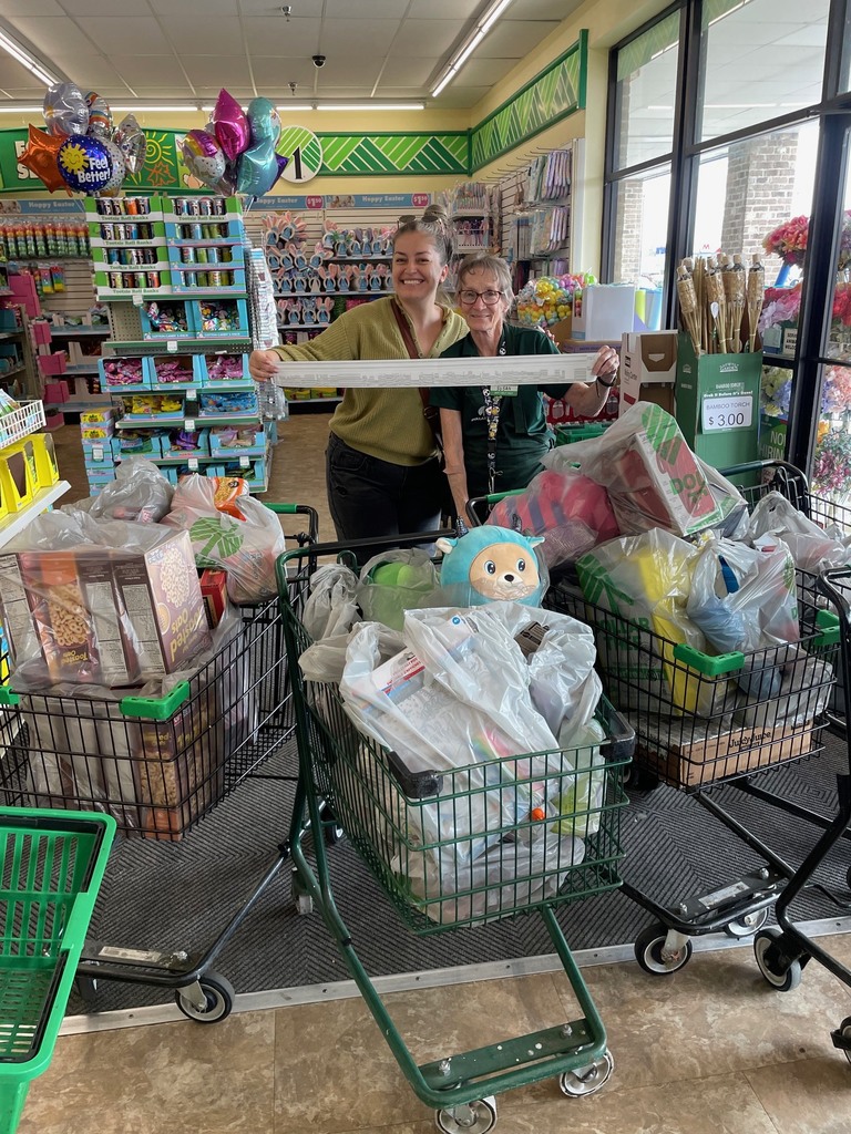 Teo adults holding a receipt, standing behind 3 grocery carts full of bags.
