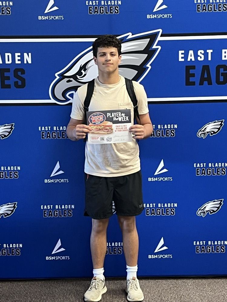 Blue background, East Bladen eagle boy and black shorts, white shirt holding jersey Mike’s sign