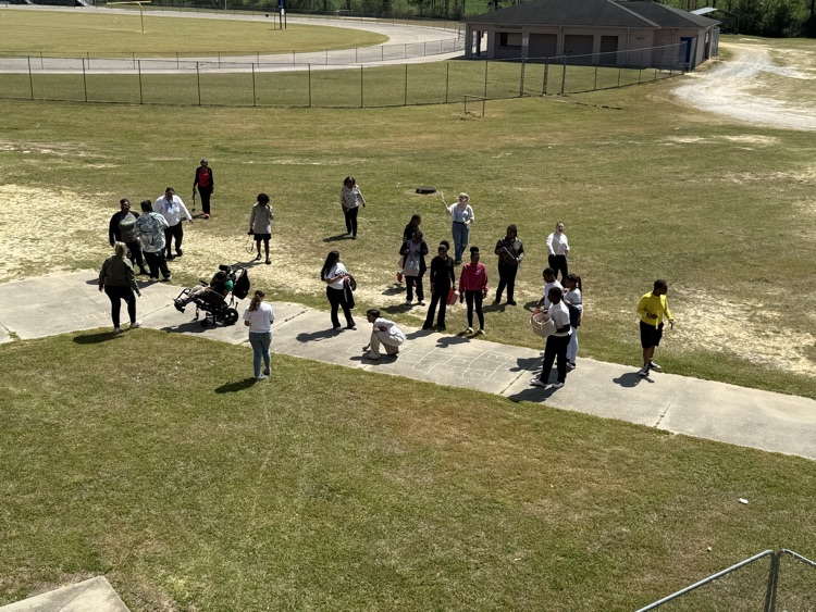 Students and teachers hunting easter eggs in the grass and playing on the sidewalk playing with chalk