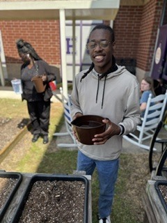 Student smiling and getting ready to water the squash