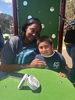 A group of elementary students and staff enjoying a sunny field trip day at a playground and park.