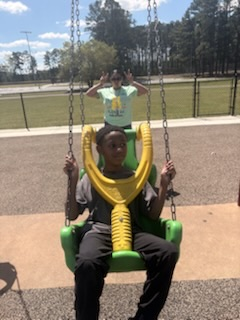 A group of elementary students and staff enjoying a sunny field trip day at a playground and park.