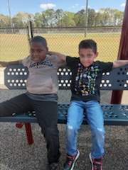 Some students sit together on benches while others climb and explore. 