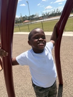 Some students sit together on benches while others climb and explore. 