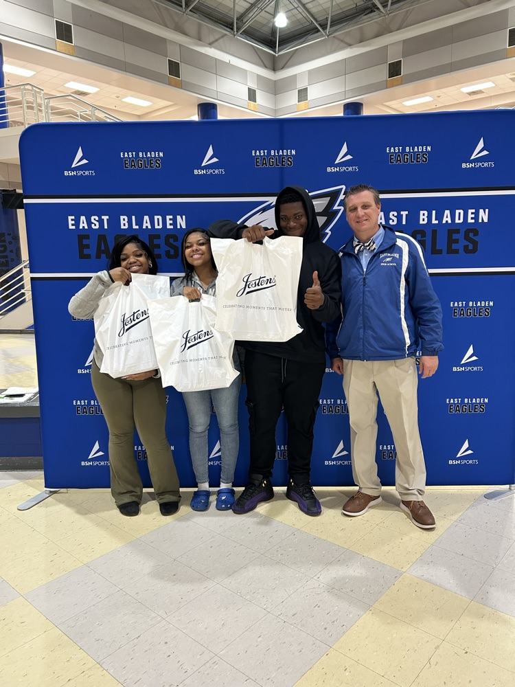 student standing in front of an East Bladen backdrop holding their white bags from Jostens