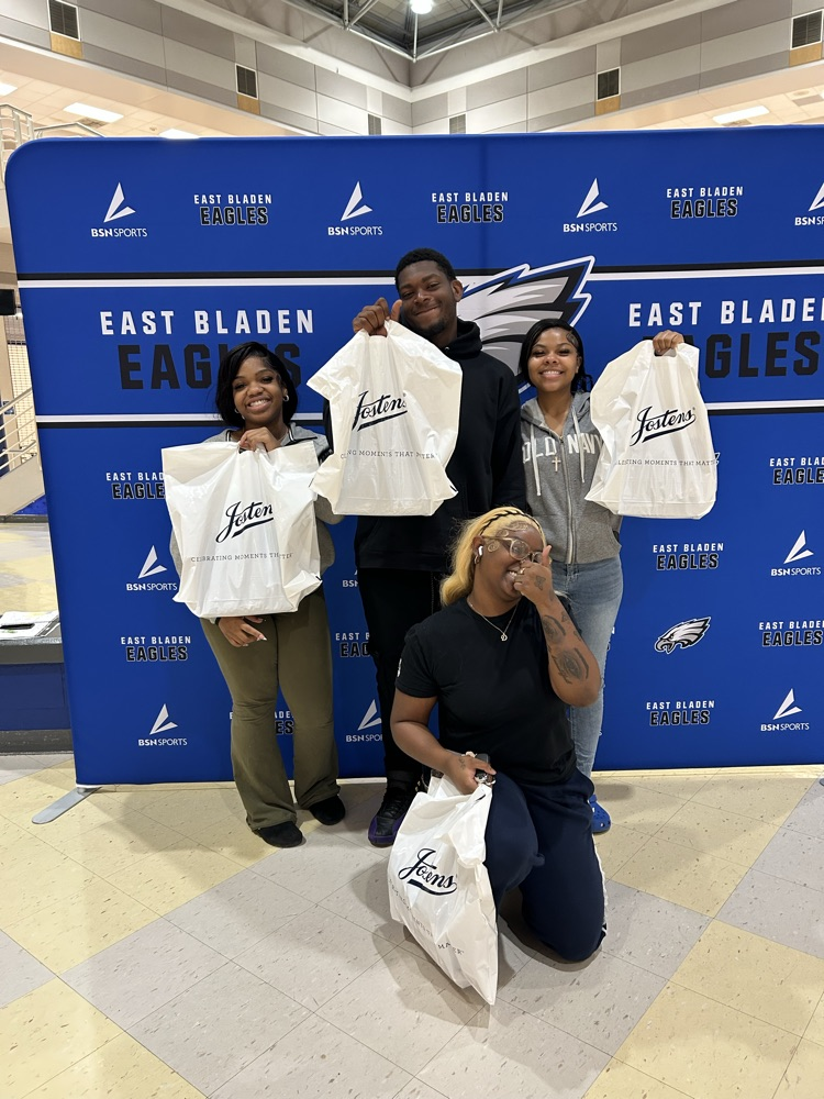 student standing in front of an East Bladen backdrop holding their white bags from Jostens
