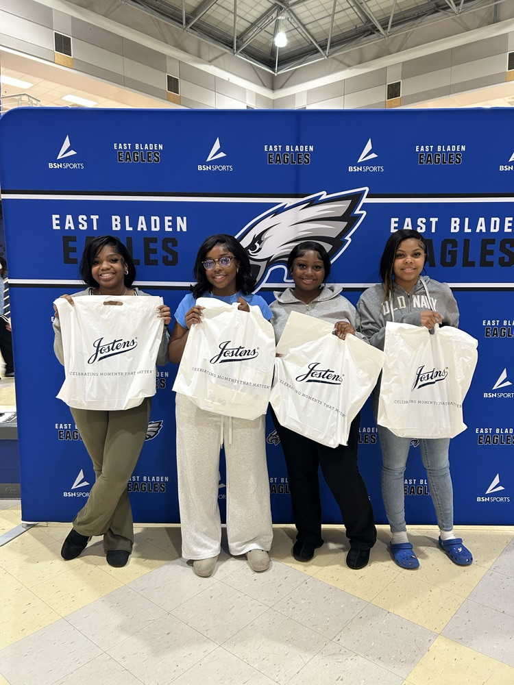 student standing in front of an East Bladen backdrop holding their white bags from Jostens