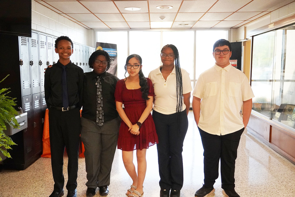 A group of five middle school students stand together smiling.
