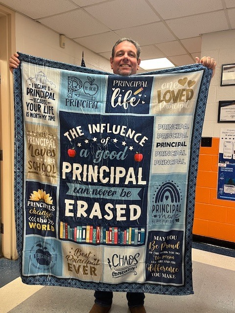 Man holding a decorative blanket celebrating principals with inspirational messages about leadership and impact.
