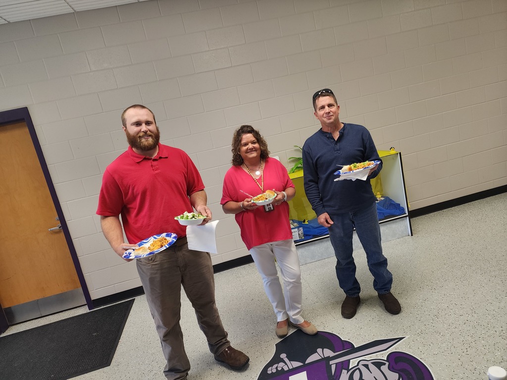 Three staff members standing together near a classroom doorway.