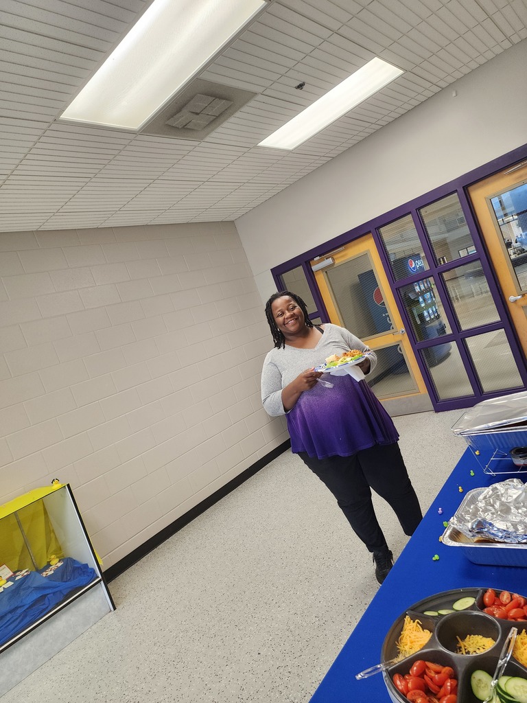 A staff member smiling in a decorated school common area